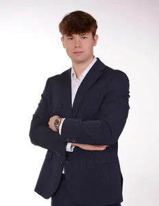 Modrá minimalistická ikona domečku s lupou, skrze lupu je vidět symbol dolaru.