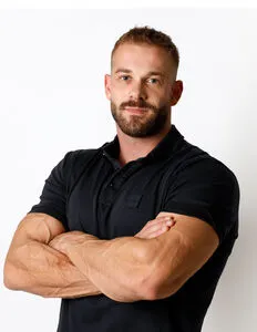 Modrá minimalistická ikona domečku s lupou, skrze lupu je vidět symbol dolaru.