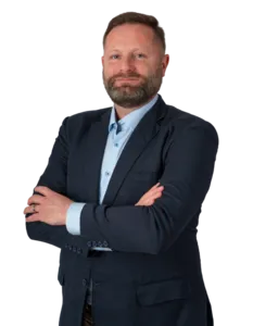 Modrá minimalistická ikona domečku s lupou, skrze lupu je vidět symbol dolaru.